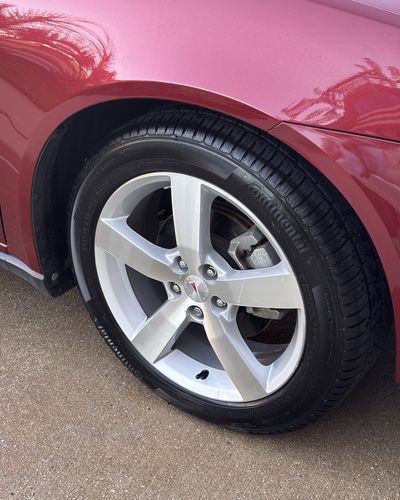 Shiny alloy wheel and dressed tire on a red Pontiac
